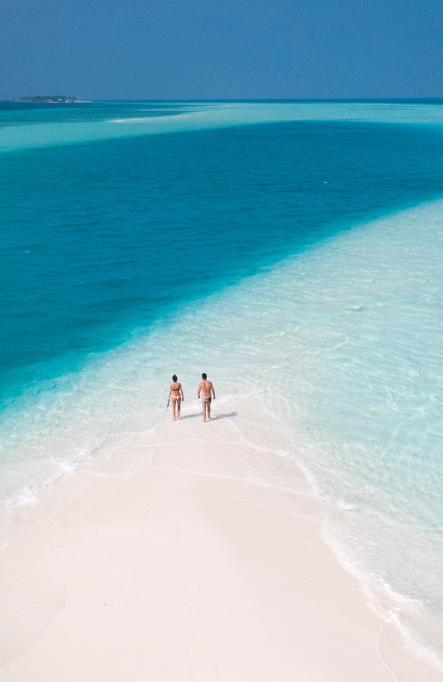 man och kvinna promenerar på en strand i maldiverna